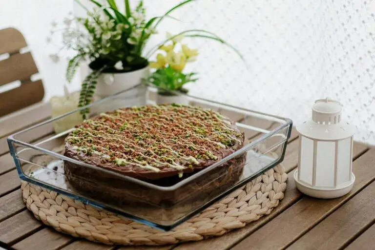 A beautifully decorated homemade chocolate cake topped with pistachios in a cozy setting.