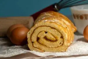 Close-up of a freshly baked roll cake with baking ingredients.