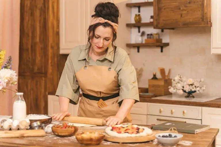 A woman kneading dough and preparing a delicious homemade fruit tart in a cozy kitchen setting.