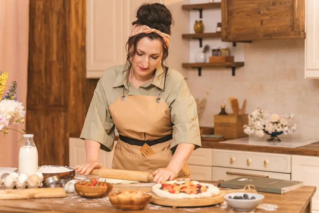 A woman kneading dough and preparing a delicious homemade fruit tart in a cozy kitchen setting.