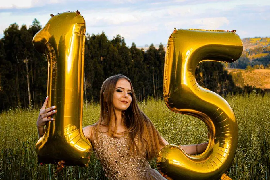 Teen girl celebrating her fifteenth birthday with golden balloons in an outdoor meadow.