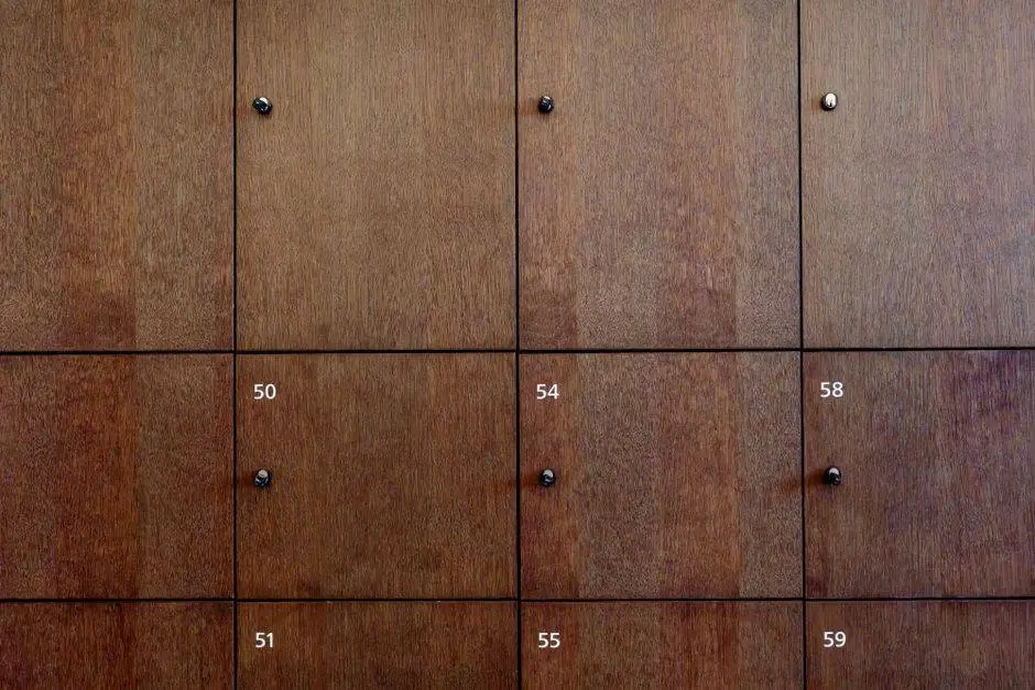 Close-up of wooden locker doors with numbers and knob handles.