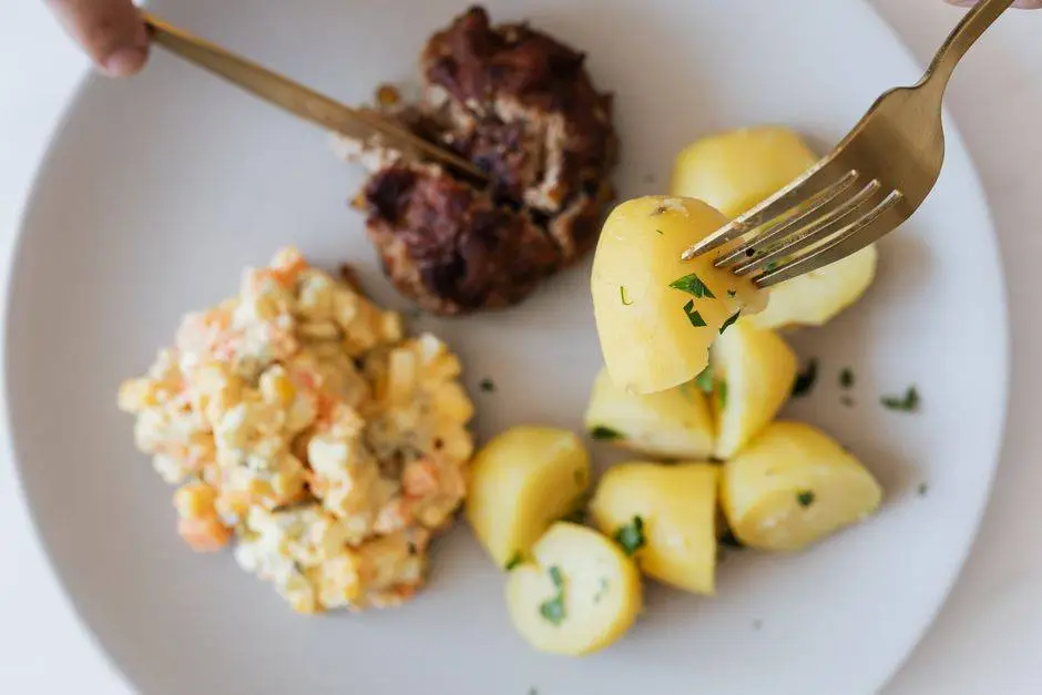 Top view of crop unrecognizable person eating fried juicy beef cutlet near delicious Russian salad with meat and boiled potatoes topped with parsley