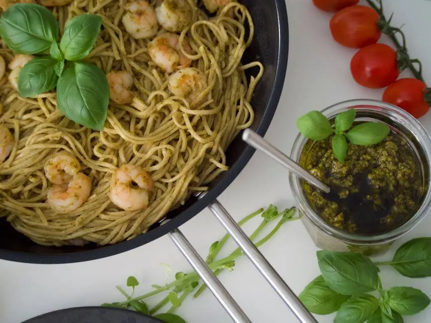 Delicious shrimp pesto pasta garnished with basil, captured from above.