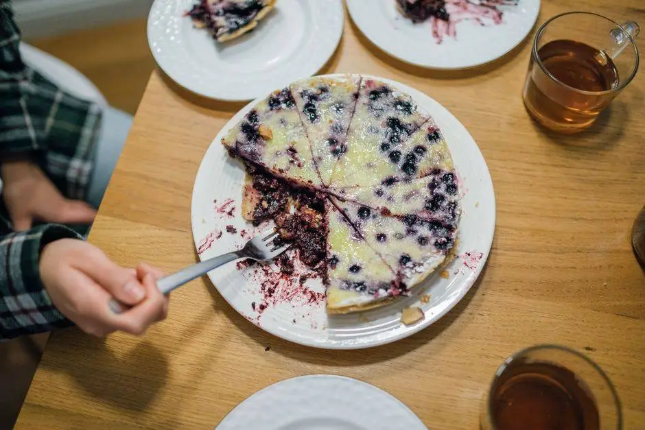 A delicious homemade blueberry pie with a fork held by a hand, perfect for dessert lovers.