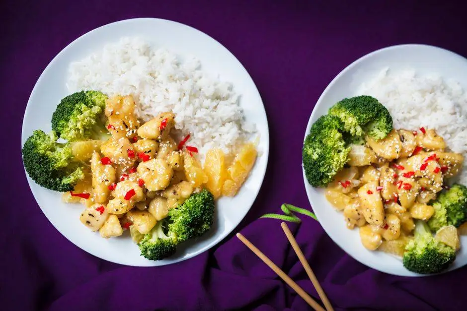 Top view of Asian chicken stir fry with rice and broccoli on a white plate.